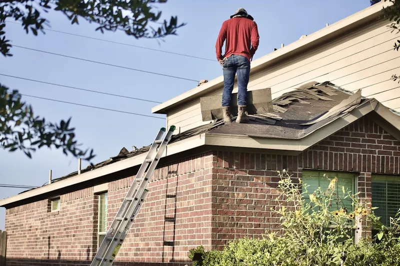 Professional roofer working on a residential roof in Ira